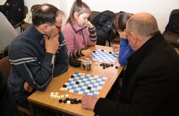 Šeimų laisvalaikis prie šaškių lentų